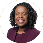 Portrait photo of woman in dark purple top smiling, in a circe