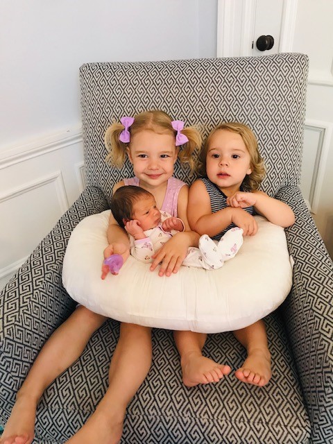 Young girls hold their newborn sister