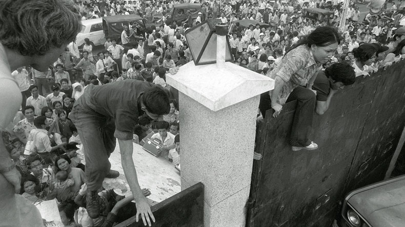 Mobs of South Vietnamese civilians scale the 14-foot wall of the U.S. Embassy in Saigon, April 29, 1975, trying to reach evacuation helicopters as the last Americans departed from Vietnam. (AP Photo)