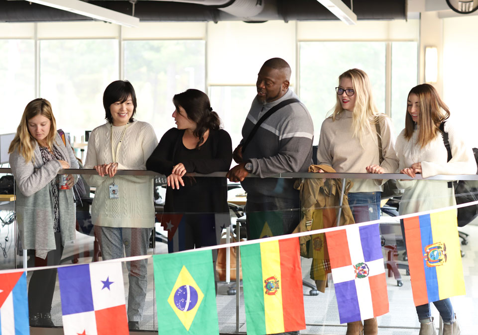 Group of people looking to open second floor, with a string of country flags hanging below them