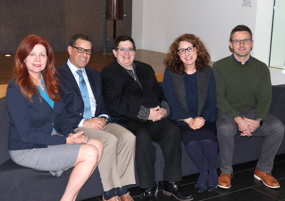 Group of men and women sitting on couch smiling at camera