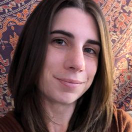 Profile photo of smiling white female with long brown hair and tapestry-like fabric in background