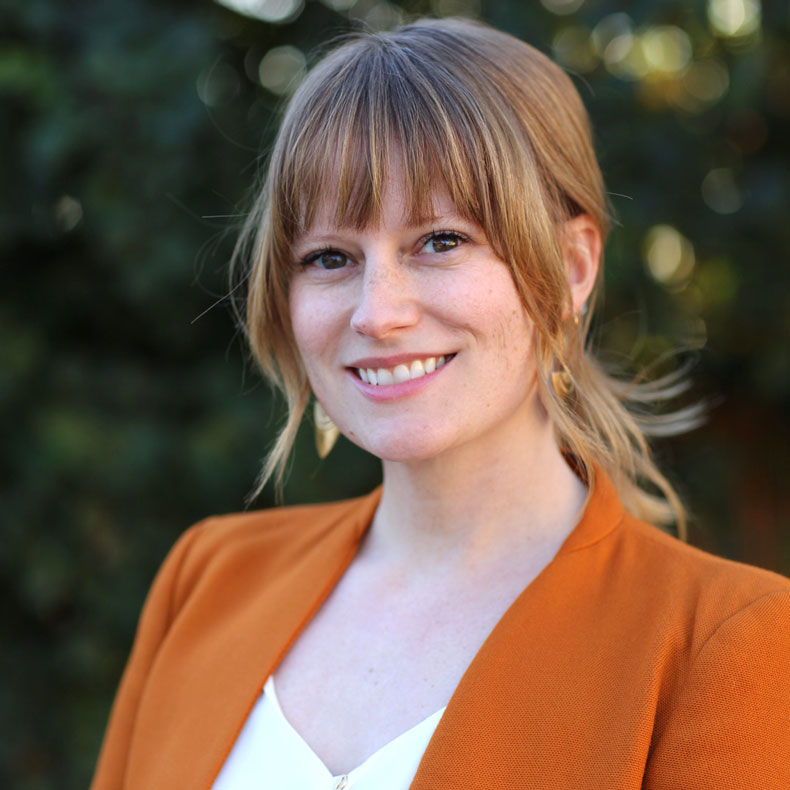 Profile photo of woman smiling in orange jacket and white top
