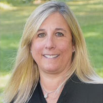 portrait photo of smiling white woman with blond hair, with grassy scene in background