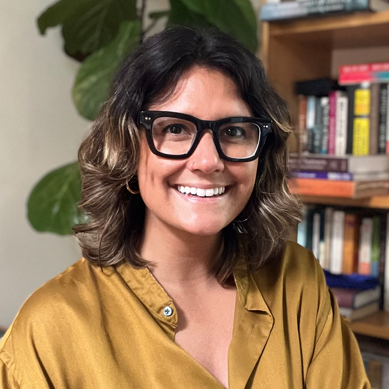 Bio Photo of Madison Natarajan, woman in gold shirt wearing black-framed glasses