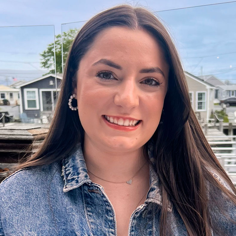 Close up portrait photo of Abby in jean shirt and outdoor waterfront background