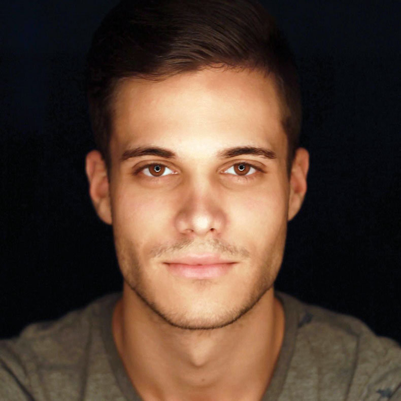 Portrait photo of Adam Tobel, smiling, with dark background