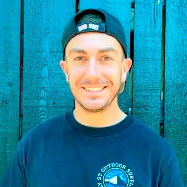 Portrait photo of Anthony Santoro Jr. wearing a baseball cap in front of slatted wood background
