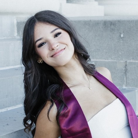 Profile photo of Elira Martin smiling in white top with purple sash
