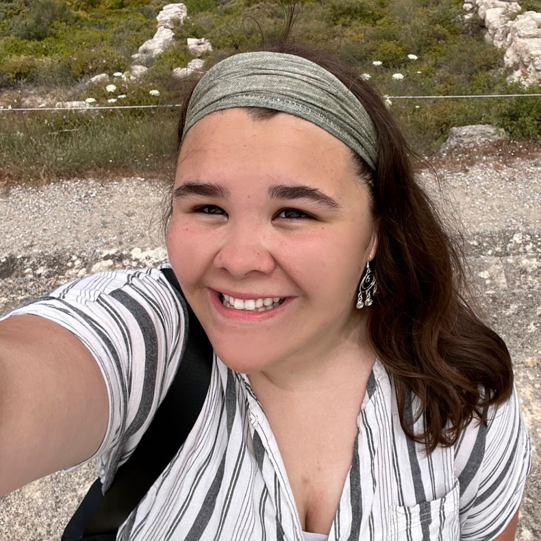 close up photo of Hannah in striped shirt and headband in outdoor setting