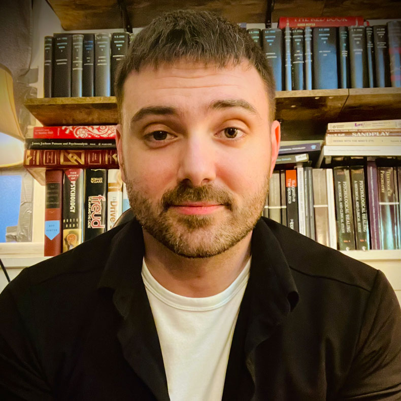 Portrait photo of Jake Nehiley with books in the background