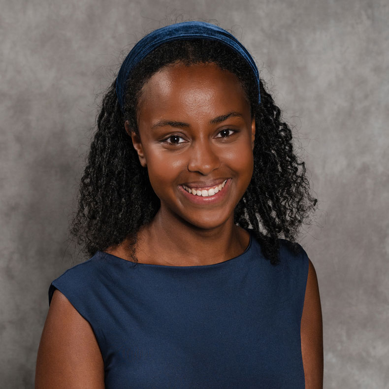 Photo of woman smiling in blue shirt with a gray background