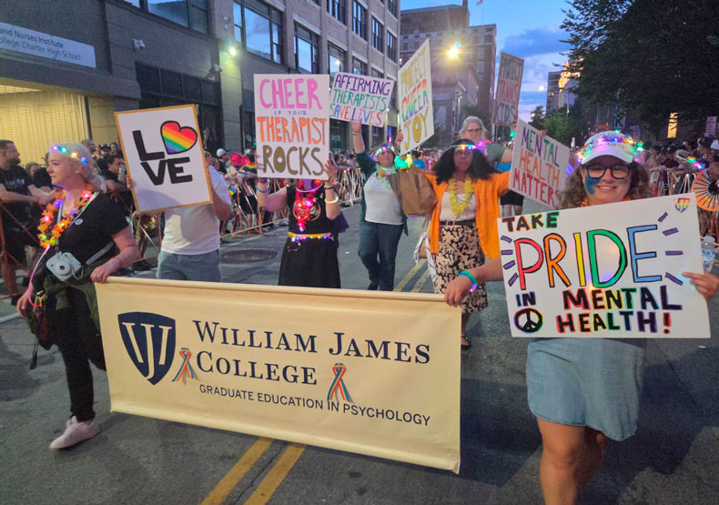 2026 LGBTQIA+ Rhode Island PRIDE Parade group of people marching in city street with banner and colorful posters