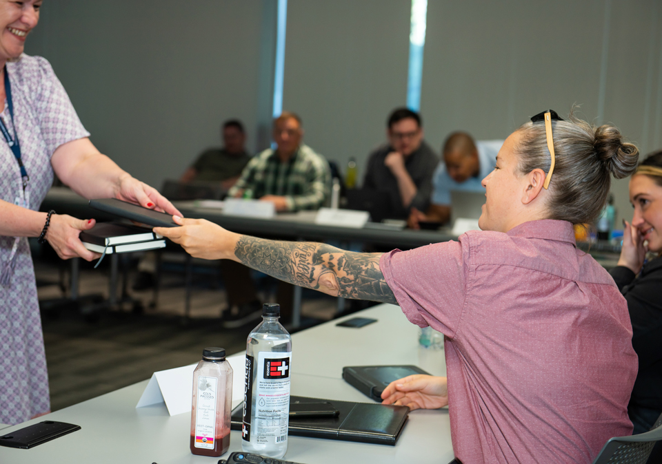 woman giving student a book in classroom