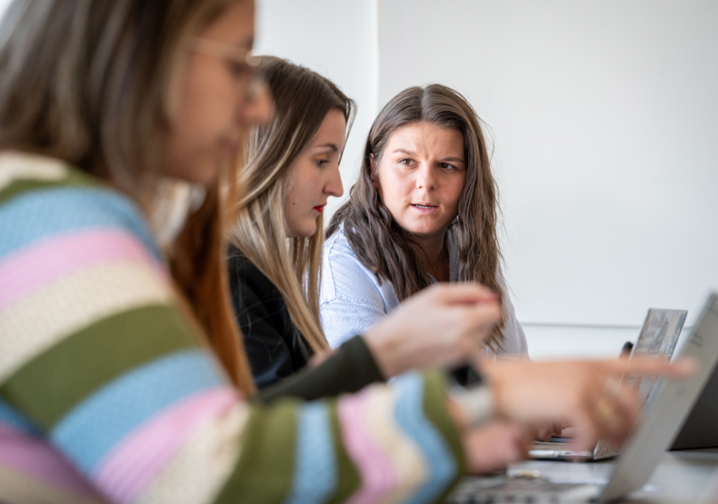 three women sitting in front of laptops