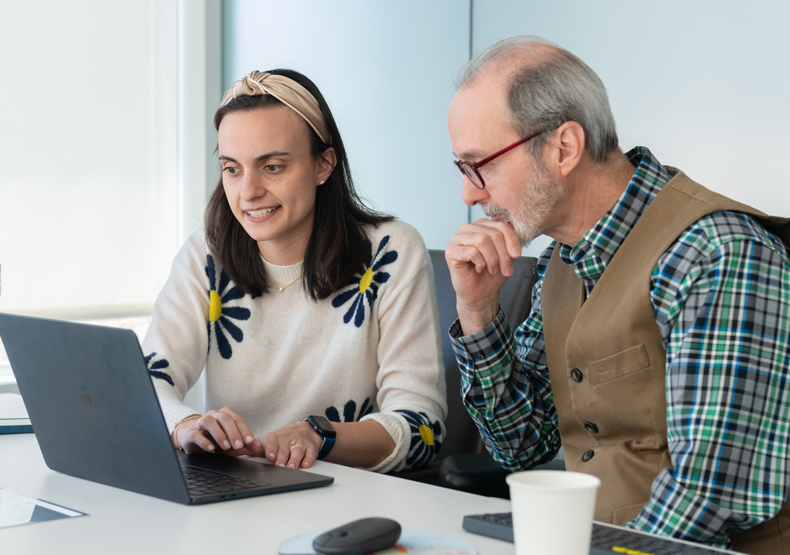 man and woman sitting in front of laptop talking