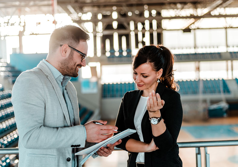Two adults talking with gym behind them