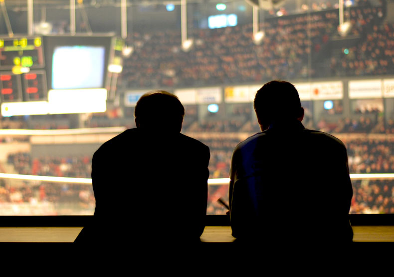 Two men silhoetted with sports arena behind them