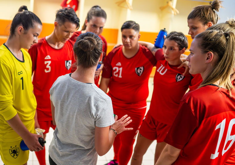 group of girls in athletic shirts huddled around coach