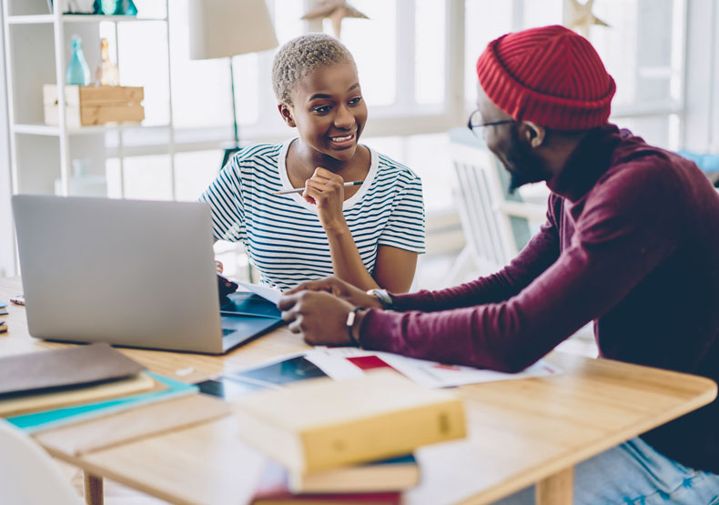 two people talking at table in front of laptop