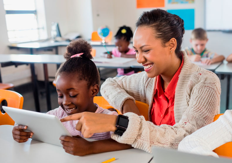 female teacher talking with young student at desk