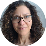 Portrait photo of smiling woman with curly brown hair and glasses