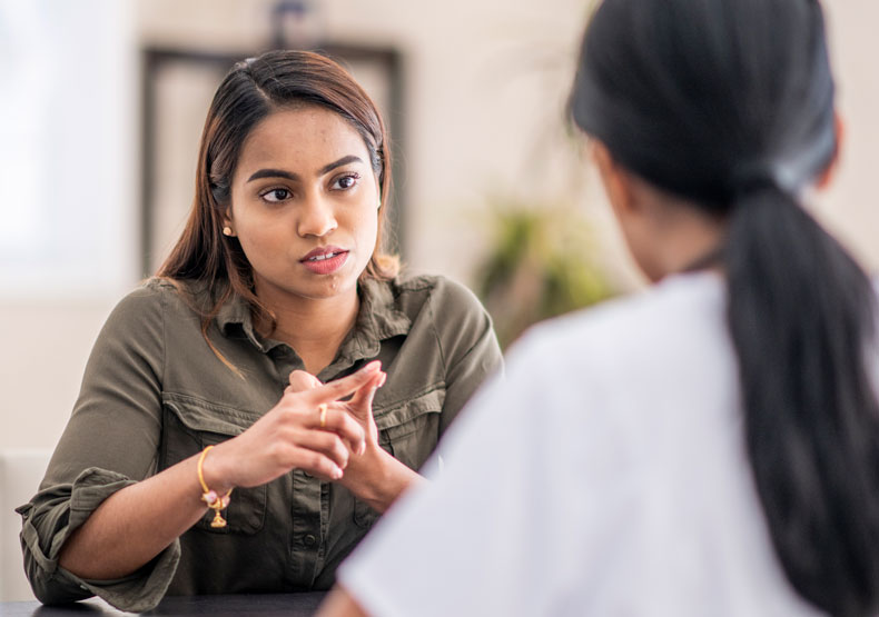 two females talking across table