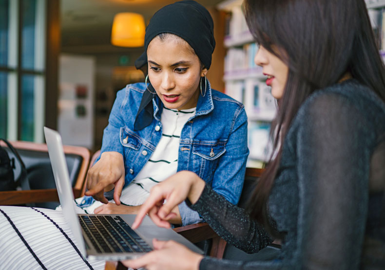 two females looking and pointing at laptop