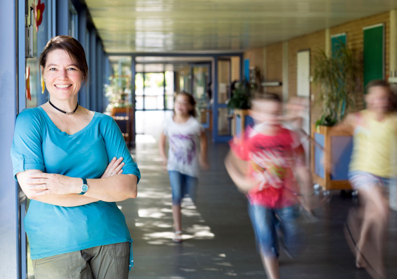 counselor in school hallway with children running