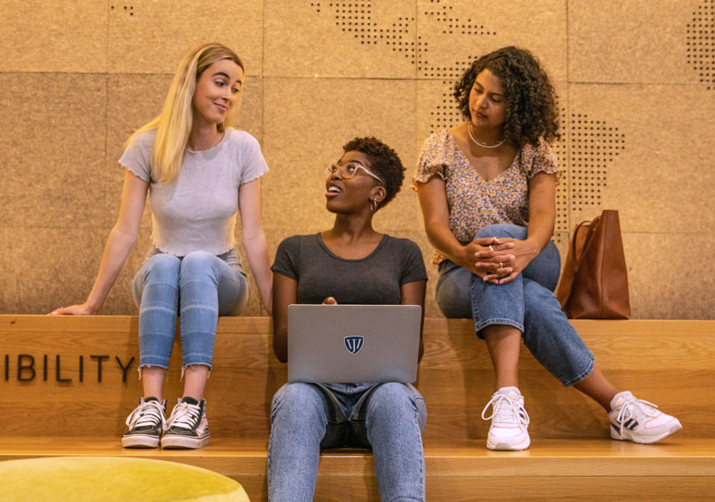 Three female students talking in campus lounge