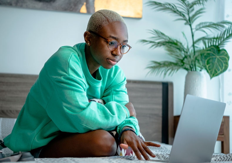 young black female at computer on her bed