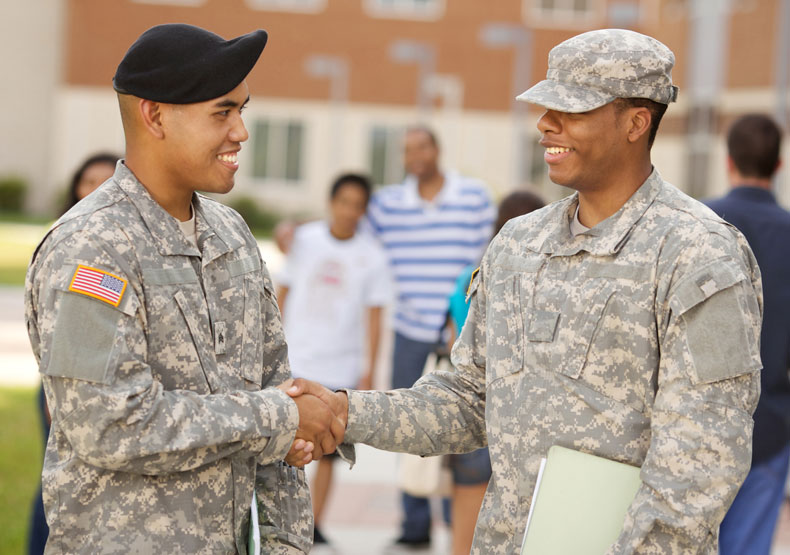 two males in military fatigues shaking hands