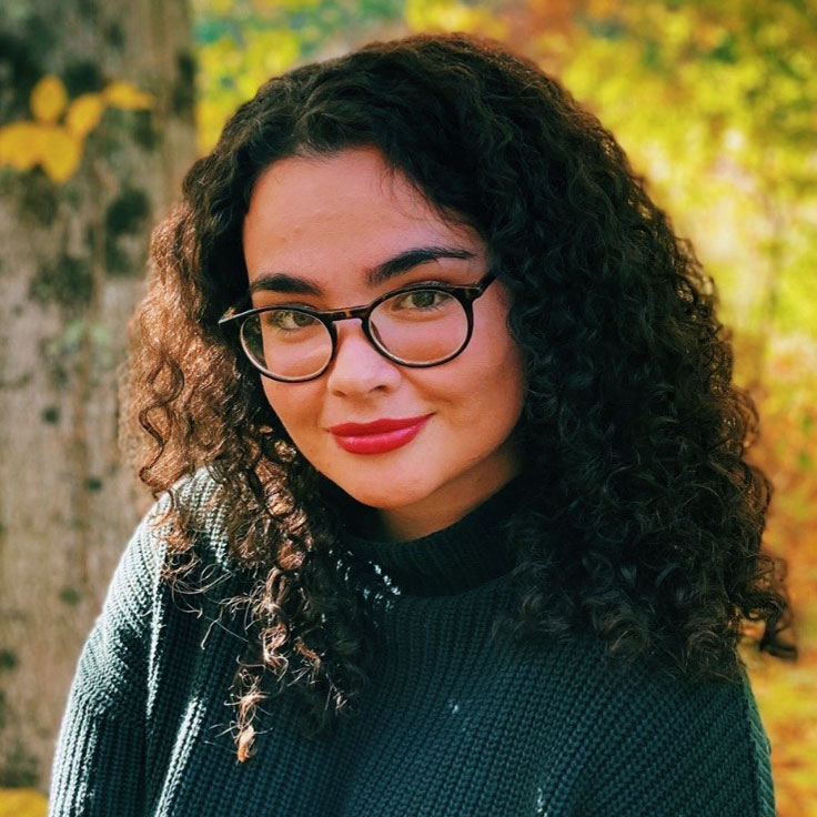 portrait photo of woman with dark hair and glasses in outdoor scene