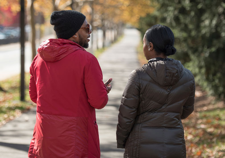 two diverse people talking while walking outside