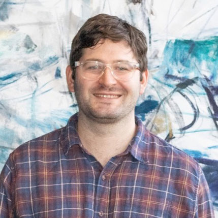 Portrait photo of smiling man, in glasses and plaid shirt with abstract backround