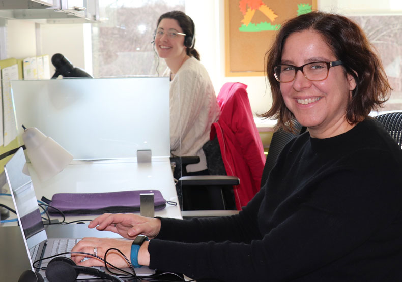 Two woman sitting at call center with computer displays in front of them