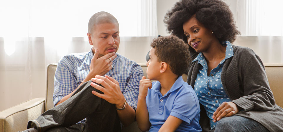 Photo of male and female adult talking to deaf child