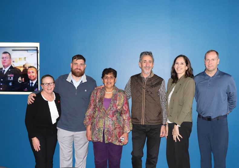 group of mena nd women posing in front of blue wall
