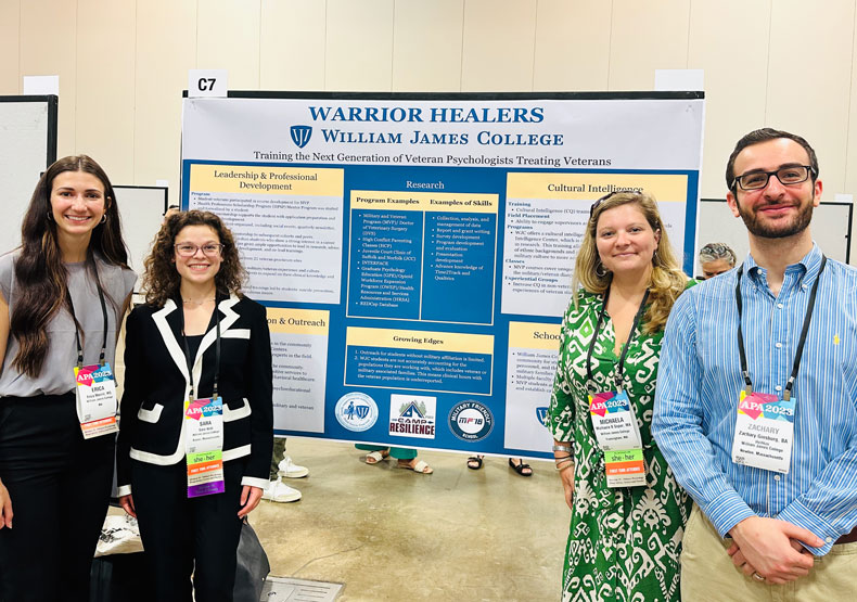Four adults posing in front of a large academic poster banner