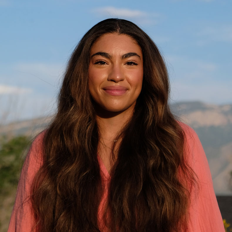 Portrait photo of woman with long dark brown hair with scenic background