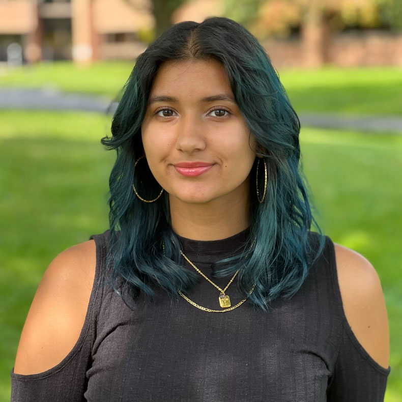 Portrait photo of woman with dark hair with scenic grassy background