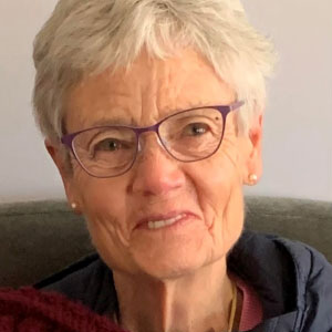 Close up photo of smiling woman with light colored hair and glasses