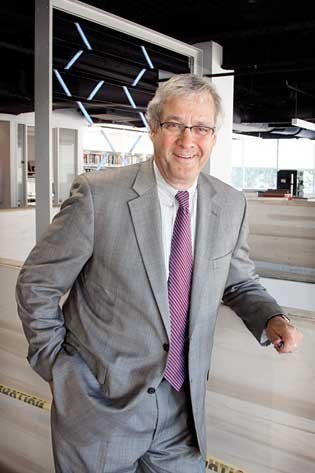 photo of smiling man wearing glasses and a suite and tie