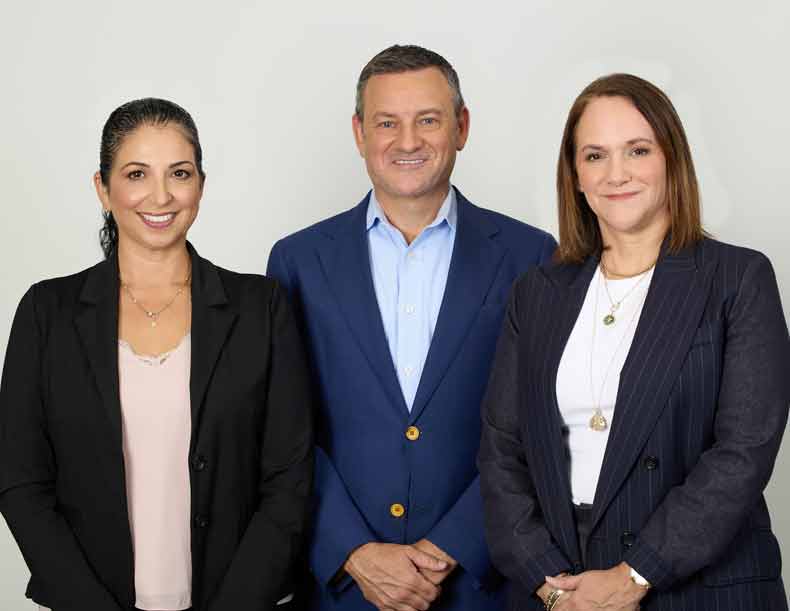 Photo of three adults posing and smiling for camera