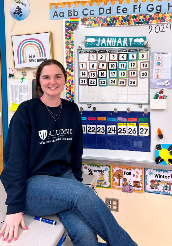 Woman sitting on desk in a school classroom