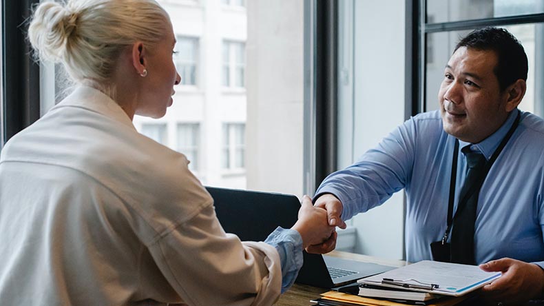 Man wearing a tie shaking hands with a young woman