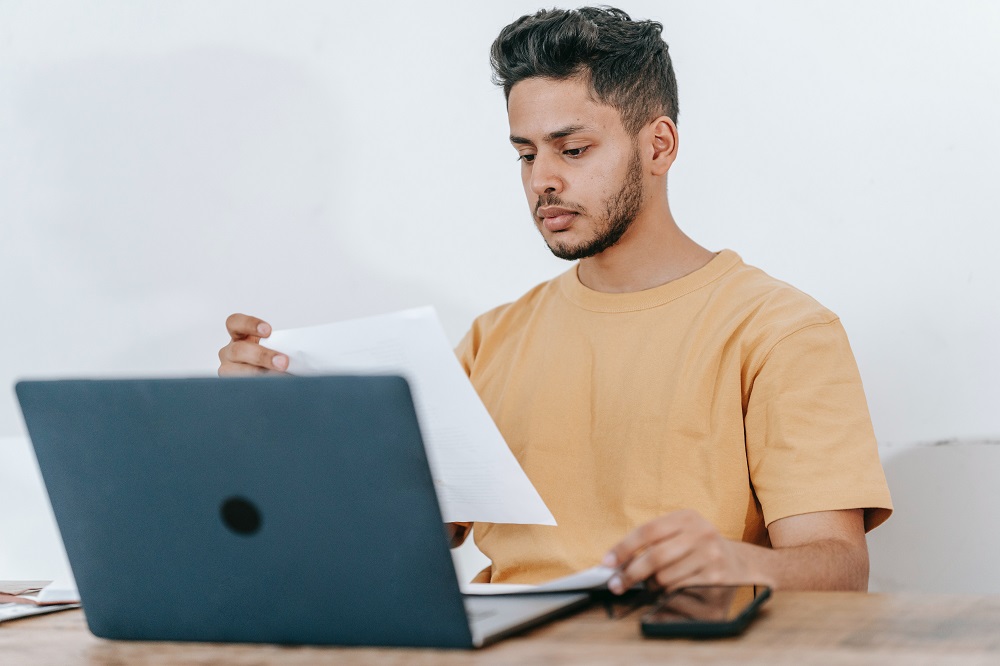 photo of man with a laptop and papers