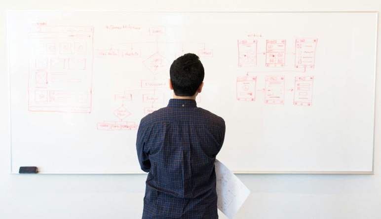 Photo of man looking at charts on a whiteboard