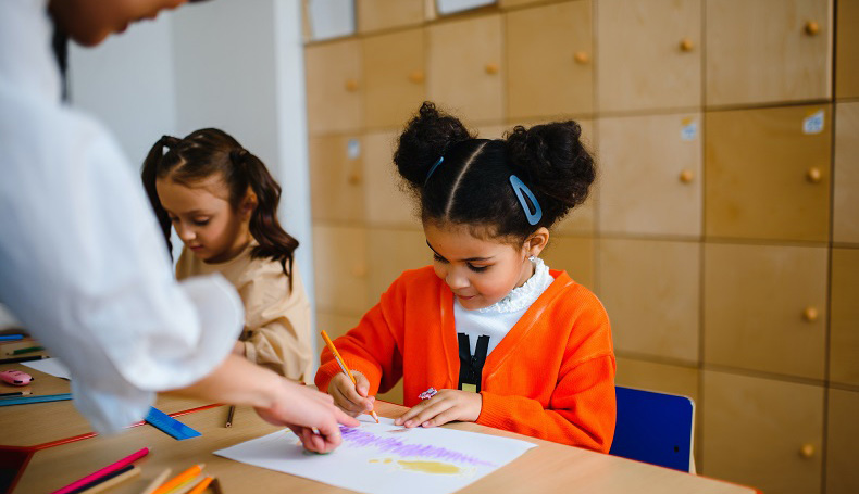 photo of an adult helping a child color at a desk