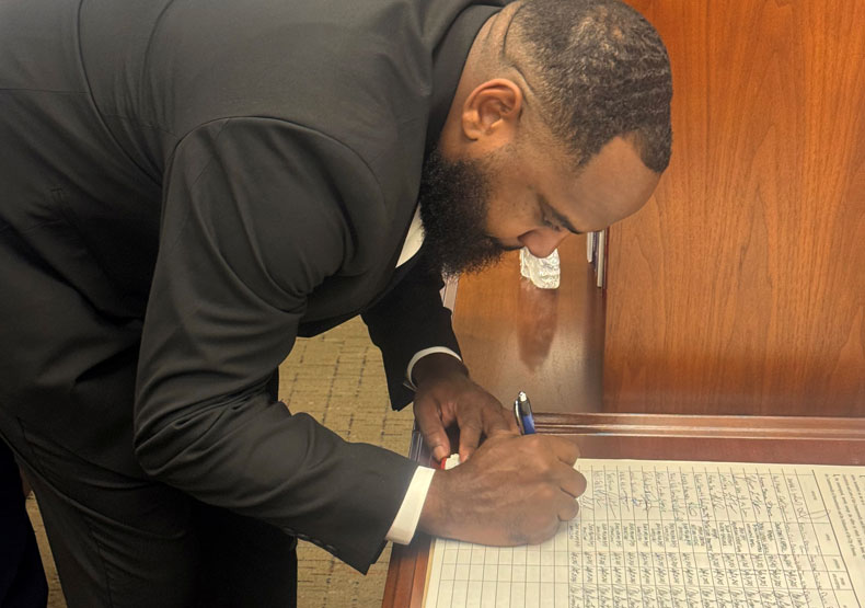 man signing notebook